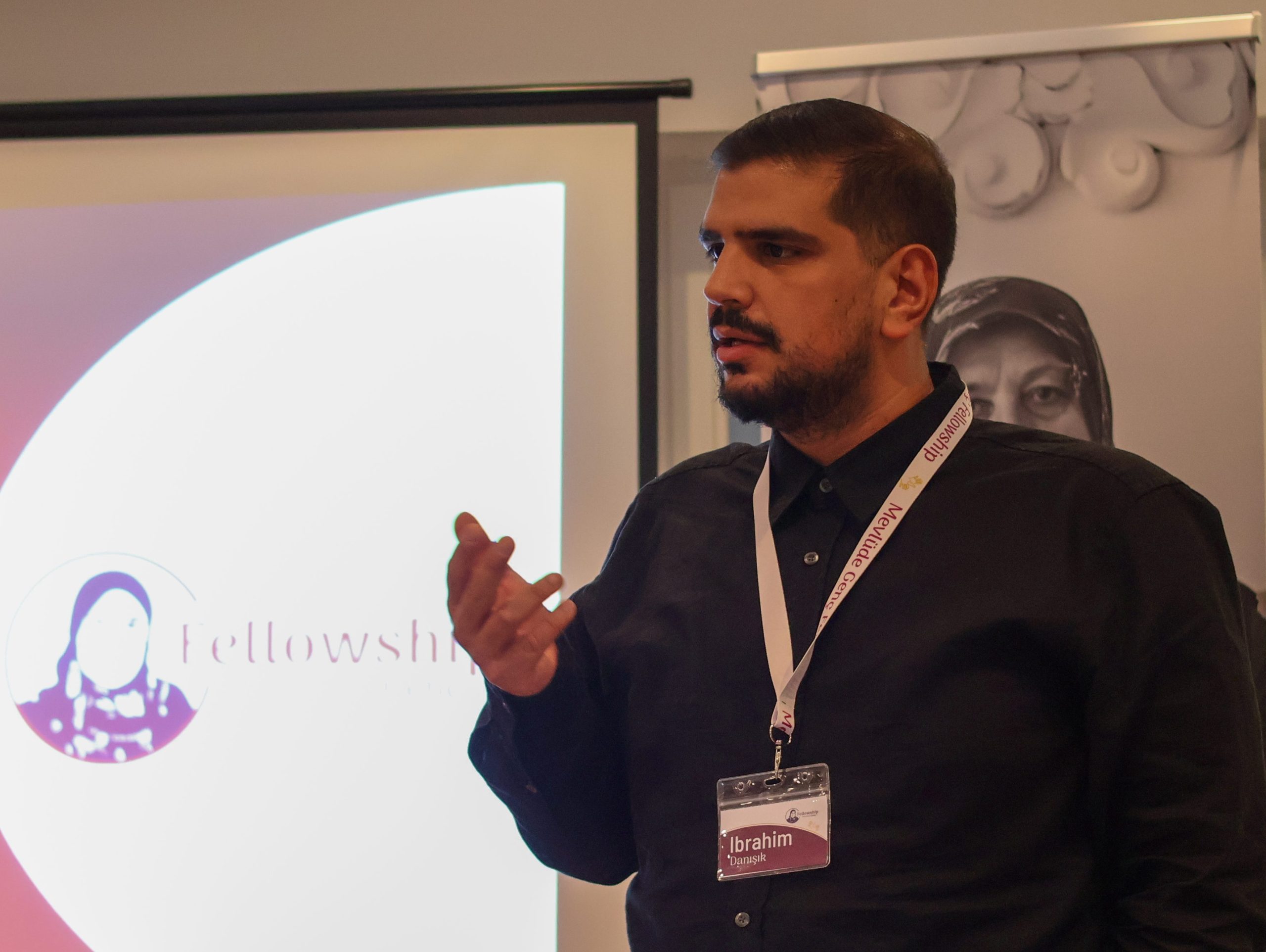 Ein junger Mann steht gestikulierend an einem Rednerpult und spricht. Hinter ihm eine Präsentation.